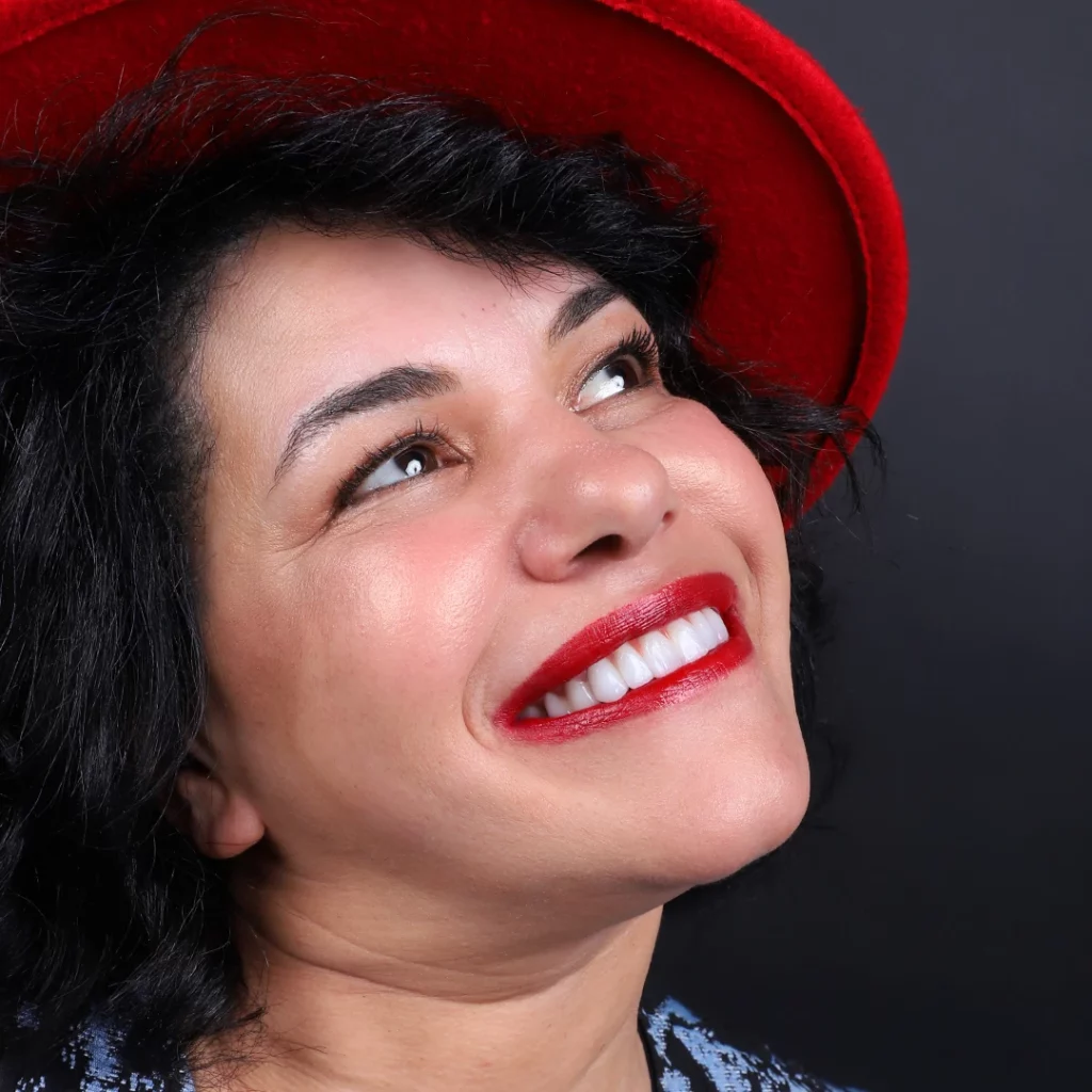 Smiling woman with bright white teeth, wearing a red hat, representing a successful Hollywood smile design