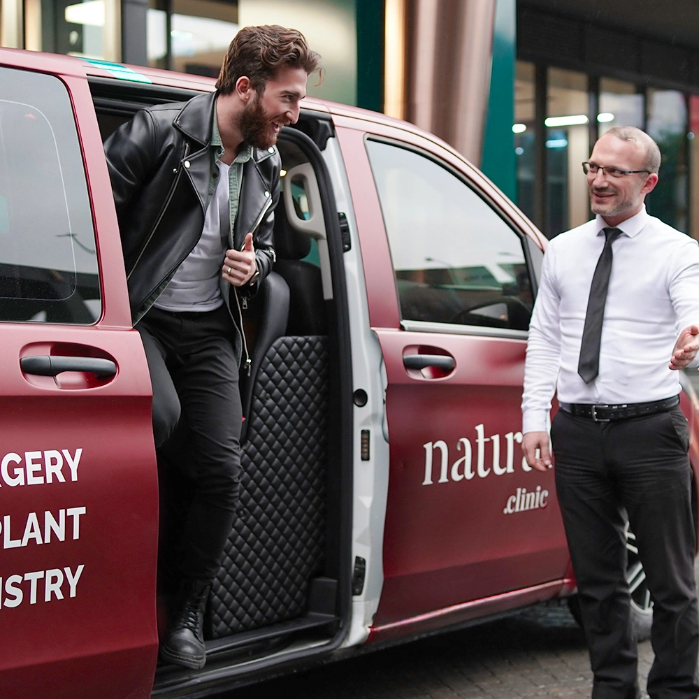 Patient arriving at the clinic for a beard hair transplant, greeted by professional staff in a welcoming environment.