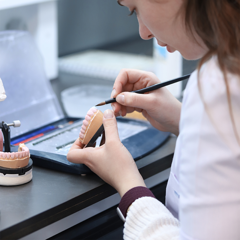 Technician crafting a custom dental crown using advanced tools and 3D technology at Natural Clinic