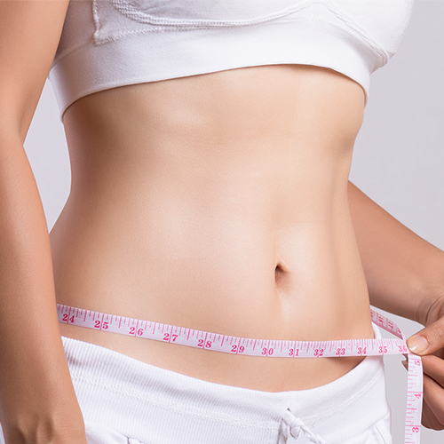 Fit woman measuring waist with tape, showcasing weight loss after gastric botox