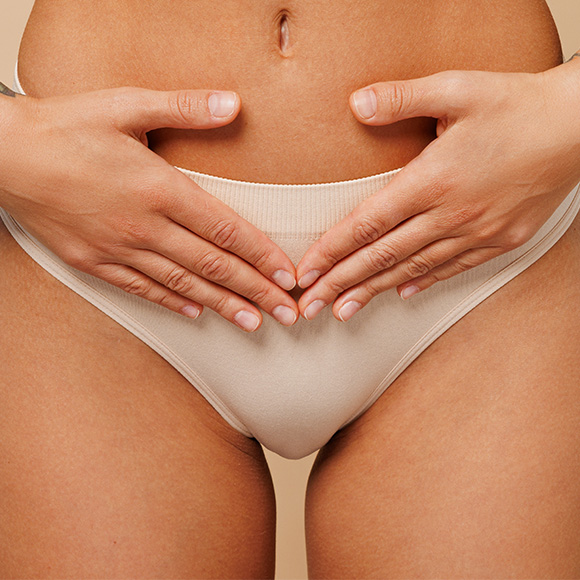 Woman covering lower abdomen, illustrating trim labiaplasty technique