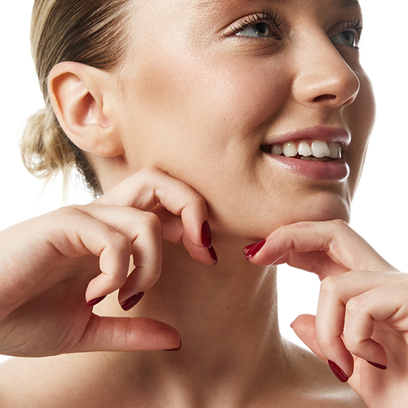 Smiling woman touching her chin, symbolizing a smooth chin liposuction recovery process